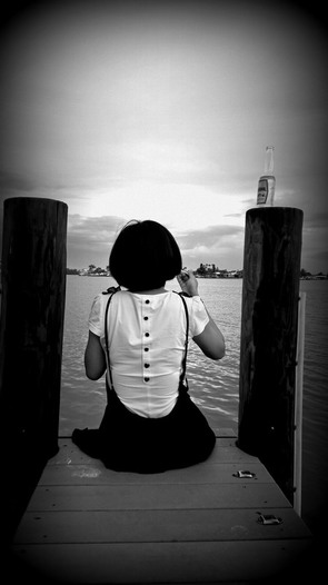 Yingchen is sitting on a dock, facing the sea, at St. Pete Beach, FL.